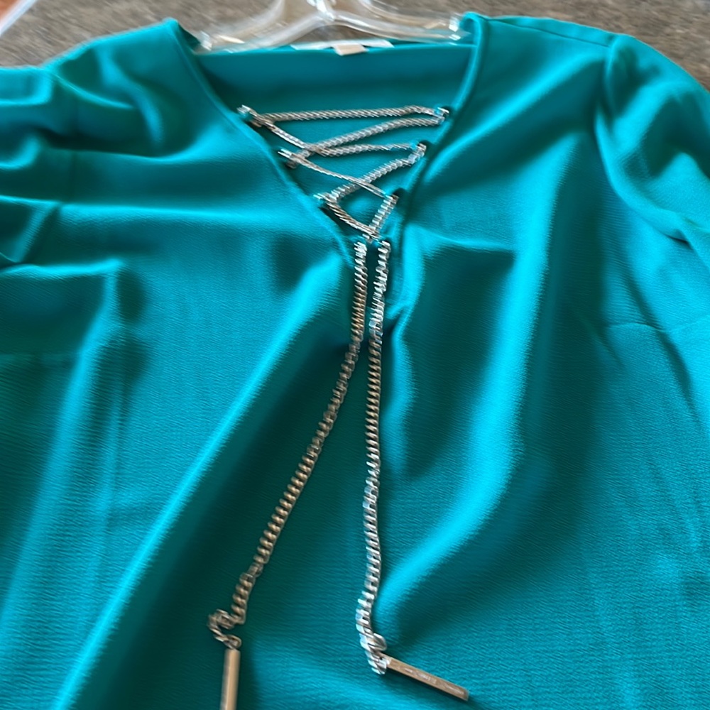 Women’s teal blouse, V-neck with chain like ties. This blouse has flare sleeves.